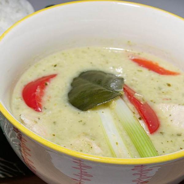 A traditional bowl of creamy, aromatic Thai green curry with chunks of chicken in a small bowl with jasmine rice